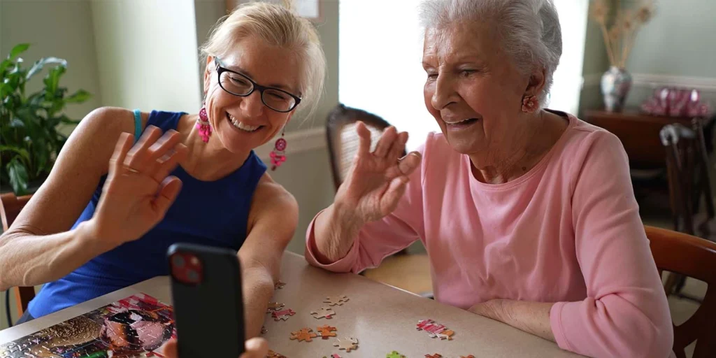 Uma mulher idosa montando quebra-cabeça com sua neta, mostrando a importância da saúde mental e parkinson.