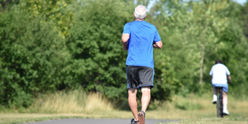 senhor de idade caminhando no parque depois de saber como funciona a cirurgia de parkinson e se beneficiar das vantagens dela