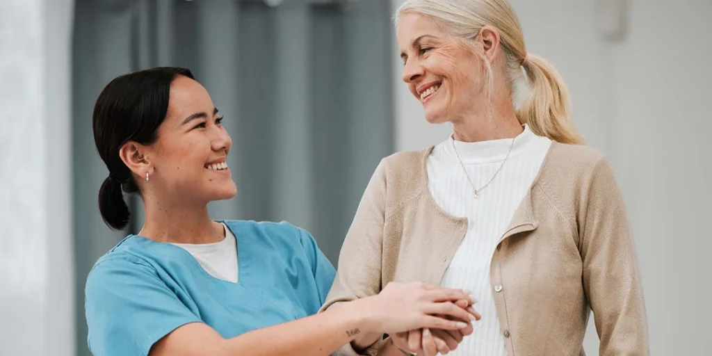 Enfermeira auxilia uma paciente, em um contexto de cuidados de saúde relacionado a parkinson e parkinsonismo.