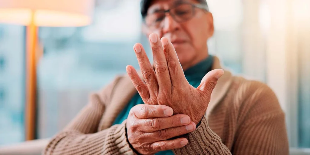 Senhor com diagnóstico de PSP segurando as mãos em momento de tremor